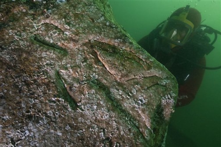 A diver inspects a quartzite block with an engraving of a Pharaoh, indicated by hieroglyphic inscriptions on the stone as Seti I, father of Ramses II, on the seabed of the harbor of Alexandria, Egypt.